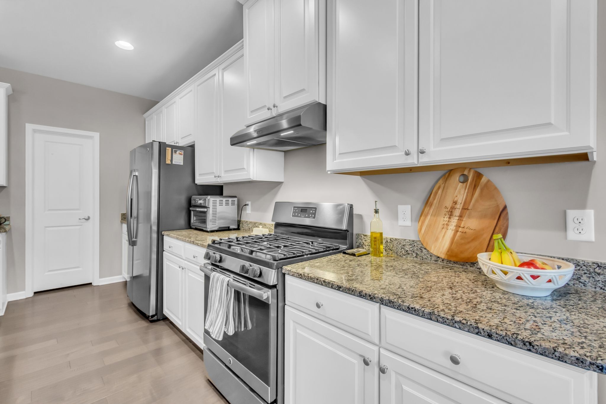 6930 Wellsford Lane College Grove, TN 37046 - Photo 12 of 44 a kitchen with stainless steel appliances granite countertop a stove a refrigerator and a white cabinets