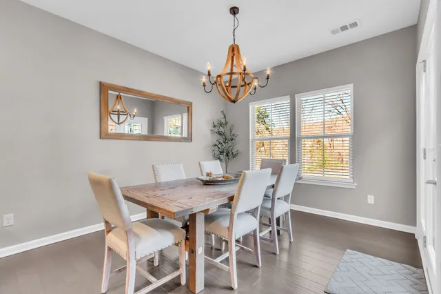 a dining room with wooden floor a chandelier a wooden table and chairs