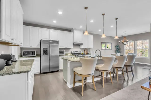 a kitchen with stainless steel appliances granite countertop a stove a refrigerator a kitchen island a dining table and chairs