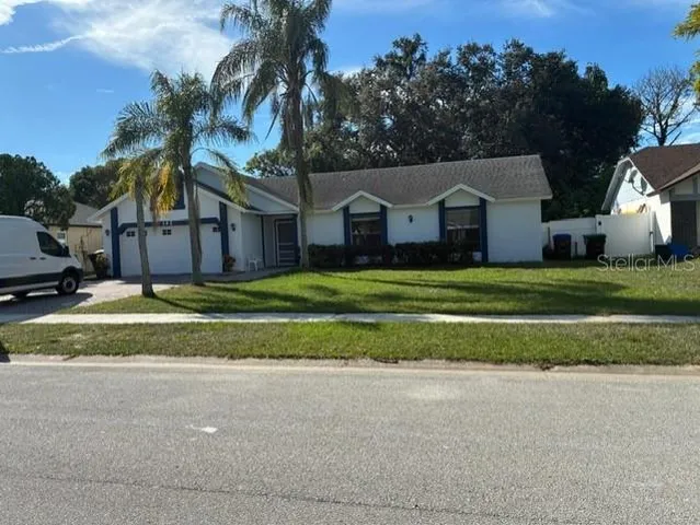 a view of a house with a big yard and palm trees