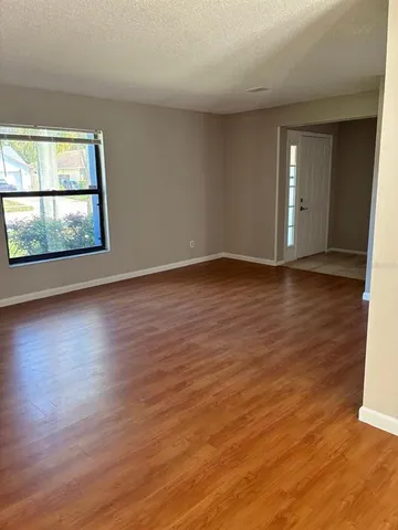 a view of an empty room with wooden floor and a window