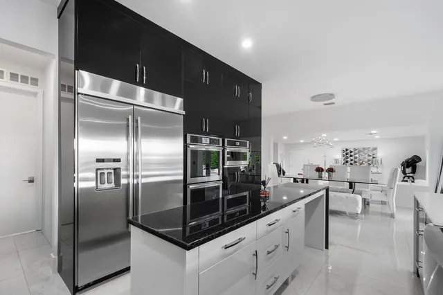 a kitchen with stainless steel appliances kitchen island granite countertop a refrigerator a sink a stove and cabinets