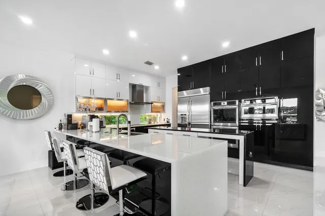 a kitchen with stainless steel appliances granite countertop a stove top oven a sink a dining table and chairs