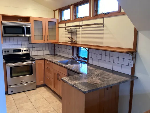 a kitchen with stainless steel appliances kitchen island granite countertop a stove a sink and a microwave
