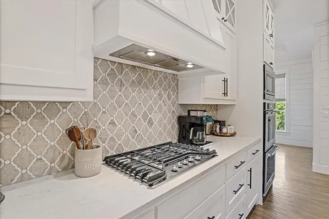 a kitchen with stainless steel appliances a refrigerator a sink dishwasher a dining table and chairs with wooden floor