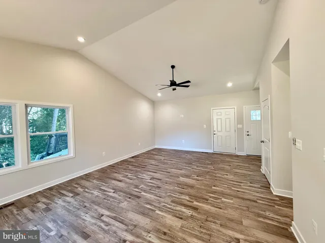 a view of an empty room with window and wooden floor