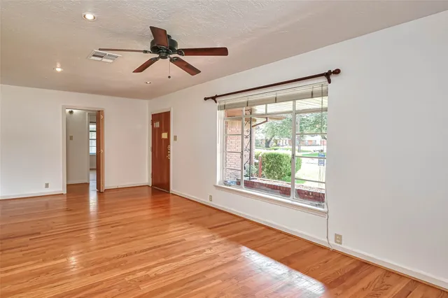 a view of an empty room with a window and wooden floor