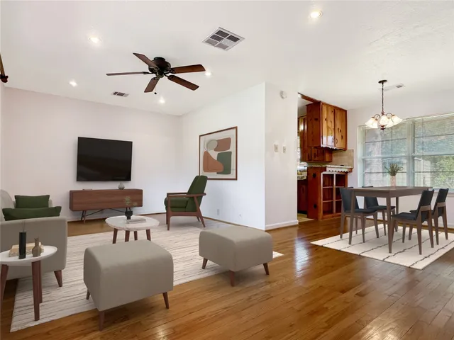 an empty room with wooden floor a ceiling fan and windows