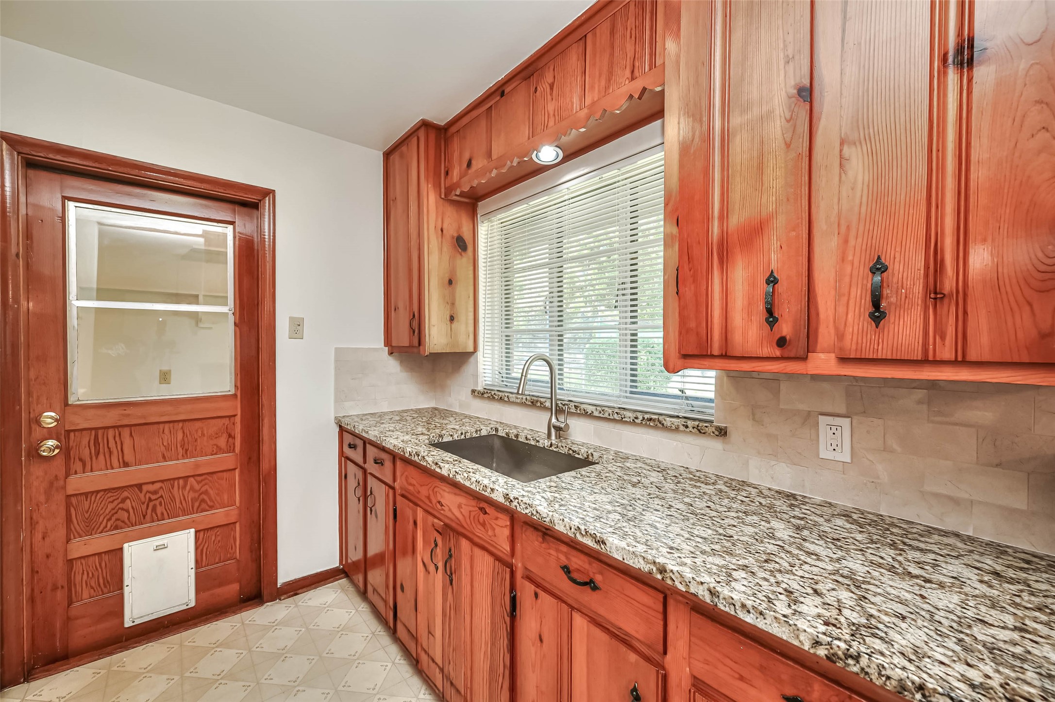 3018 Attridge Road Houston, TX 77018 - Photo 9 of 29 a kitchen with granite countertop wooden cabinets a sink and a window