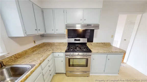 a kitchen with granite countertop a stove sink and cabinets