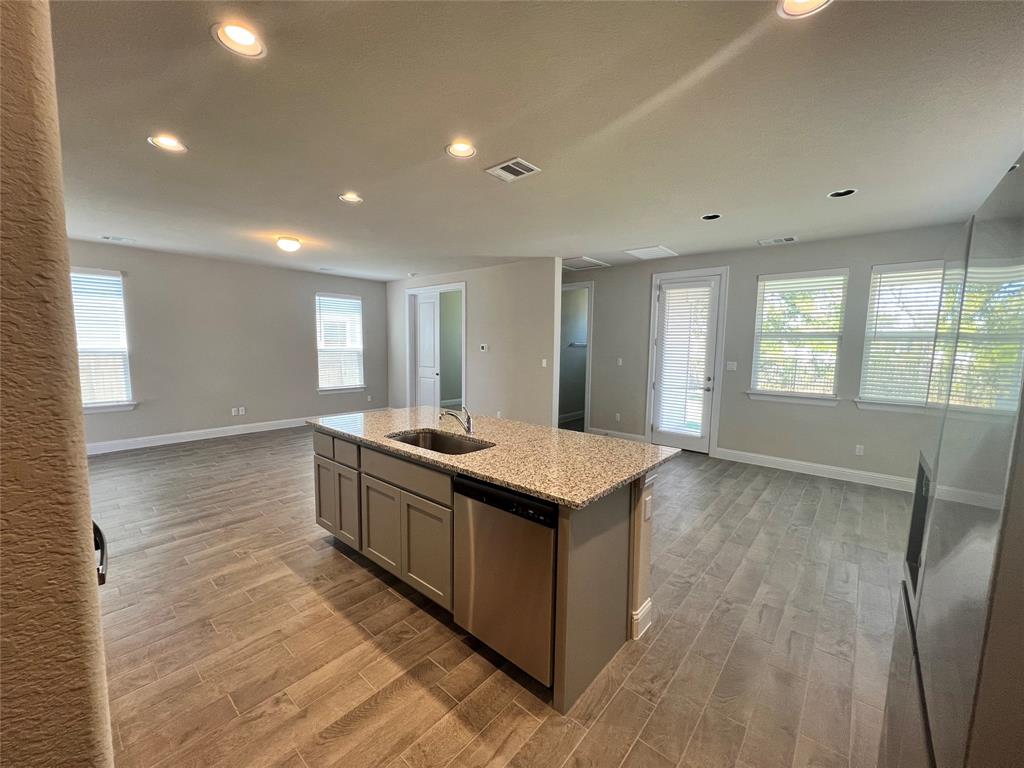 128 Free Stone Drive Georgetown, TX 78628 - Photo 27 of 29 Kitchen island with an undermount sink, a built-in dishwasher, and a stone-finish countertop