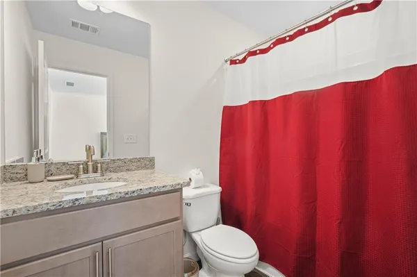 a bathroom with a granite countertop sink mirror vanity and toilet