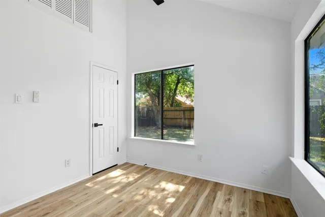a view of an empty room with wooden floor and a window