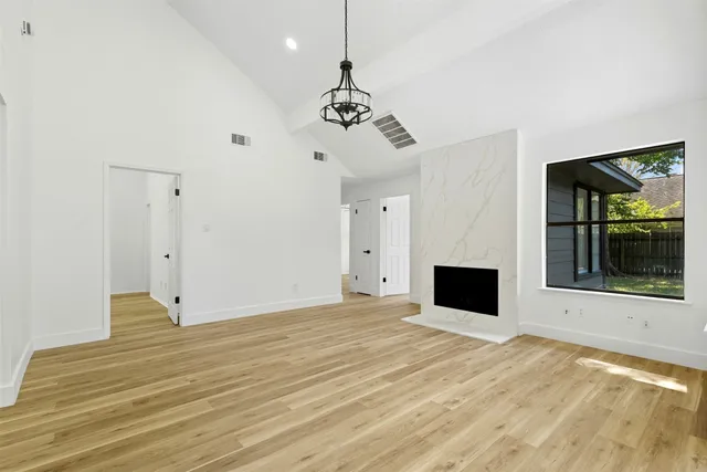 a view of an empty room with window and wooden floor