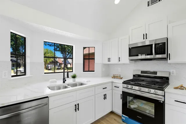 a kitchen with stainless steel appliances a stove sink microwave and cabinets