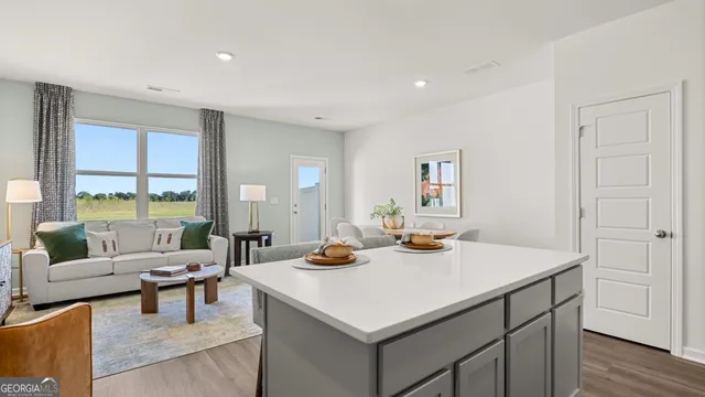 a living room with stainless steel appliances furniture and a kitchen view