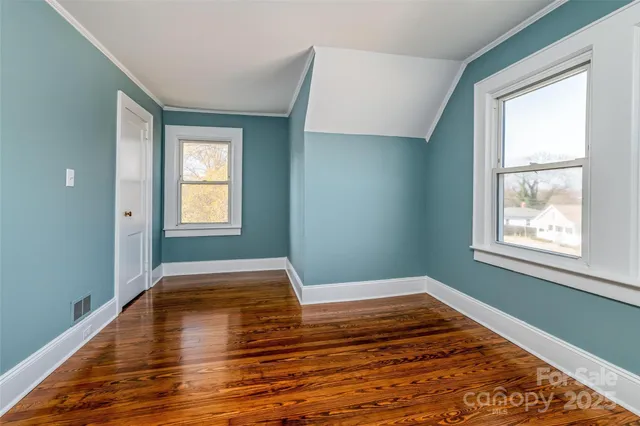 a view of empty room with window and wooden floor
