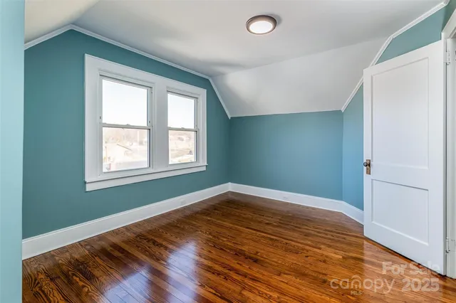 a view of empty room with window and wooden floor