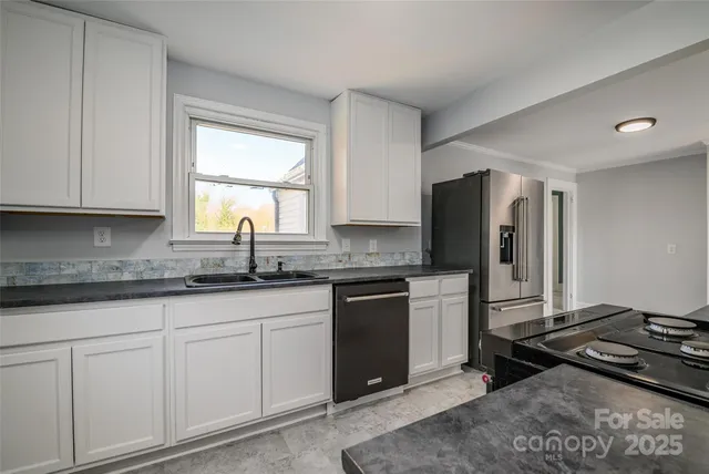 a kitchen with granite countertop a sink stove and refrigerator