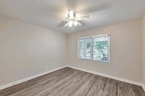 551 Wimbledon Road Northeast, Unit B Atlanta, GA 30324 - Photo 16 of 20 an empty room with wooden floor chandelier fan and windows