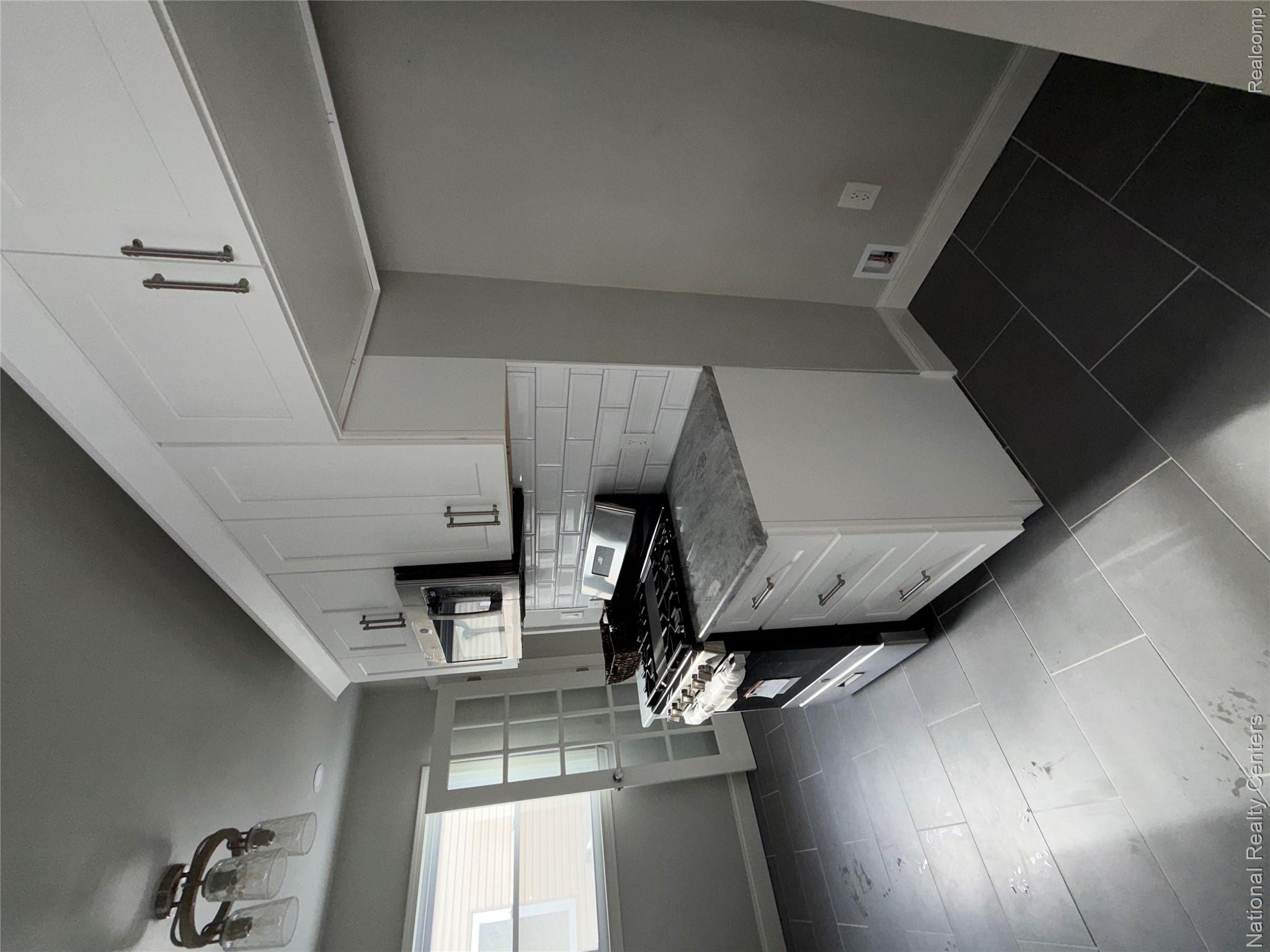 16522 Inverness Street Detroit, MI 48221 - Photo 13 of 62 Kitchen with white cabinetry, stainless steel stove, decorative backsplash, dark tile patterned flooring, and light stone countertops