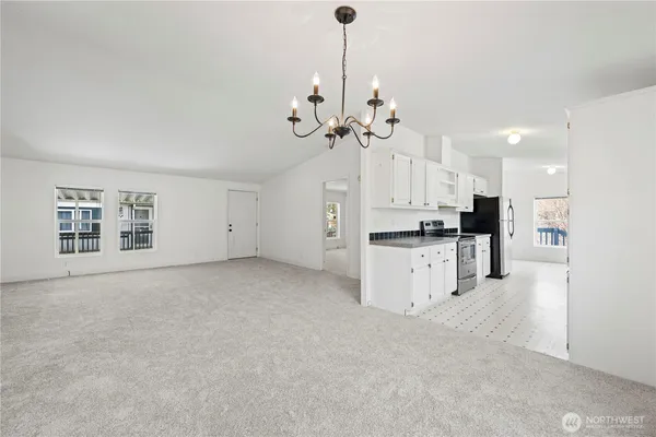 a view of an empty room with kitchen and window