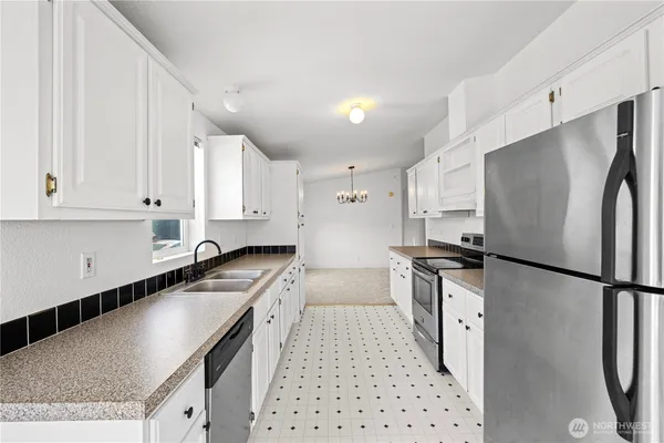 a kitchen with granite countertop a sink a counter top space stainless steel appliances and cabinets