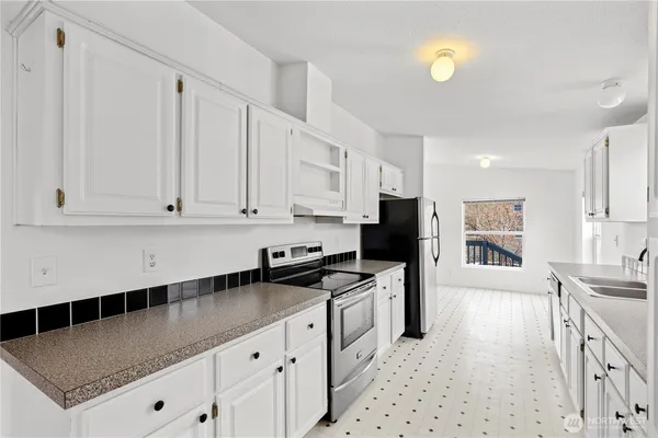 a kitchen with granite countertop a sink a stove and refrigerator