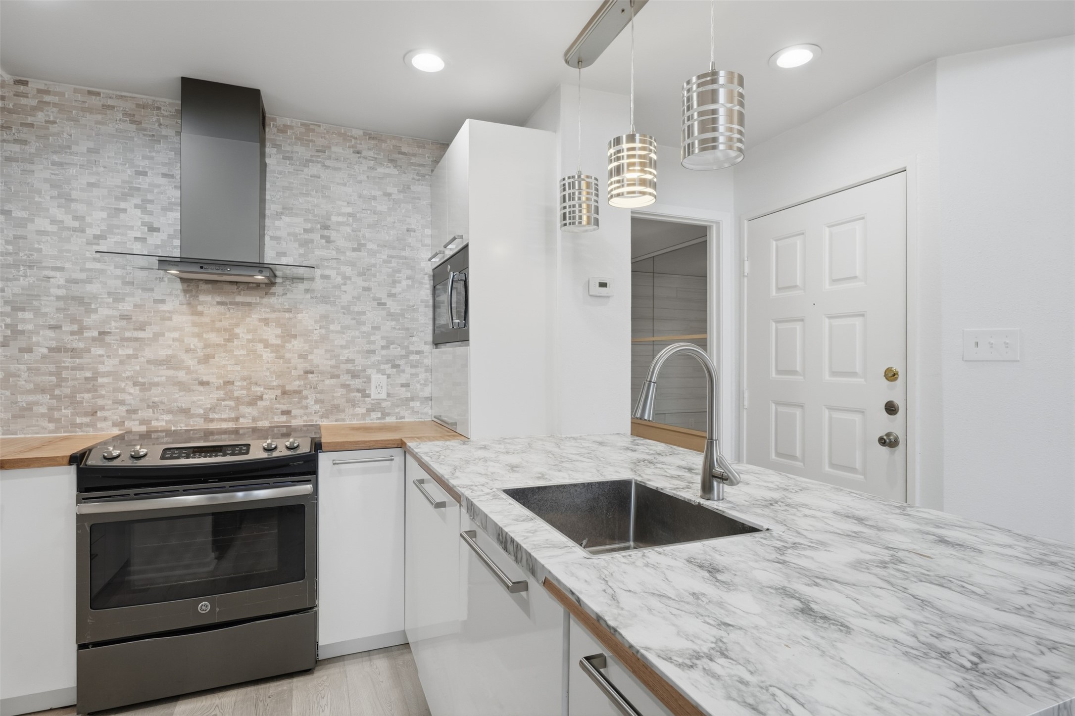 10855 Meadowglen Lane, Unit 823 Houston, TX 77042 - Photo 7 of 35 a kitchen with a sink dishwasher a stove and a refrigerator with wooden floor