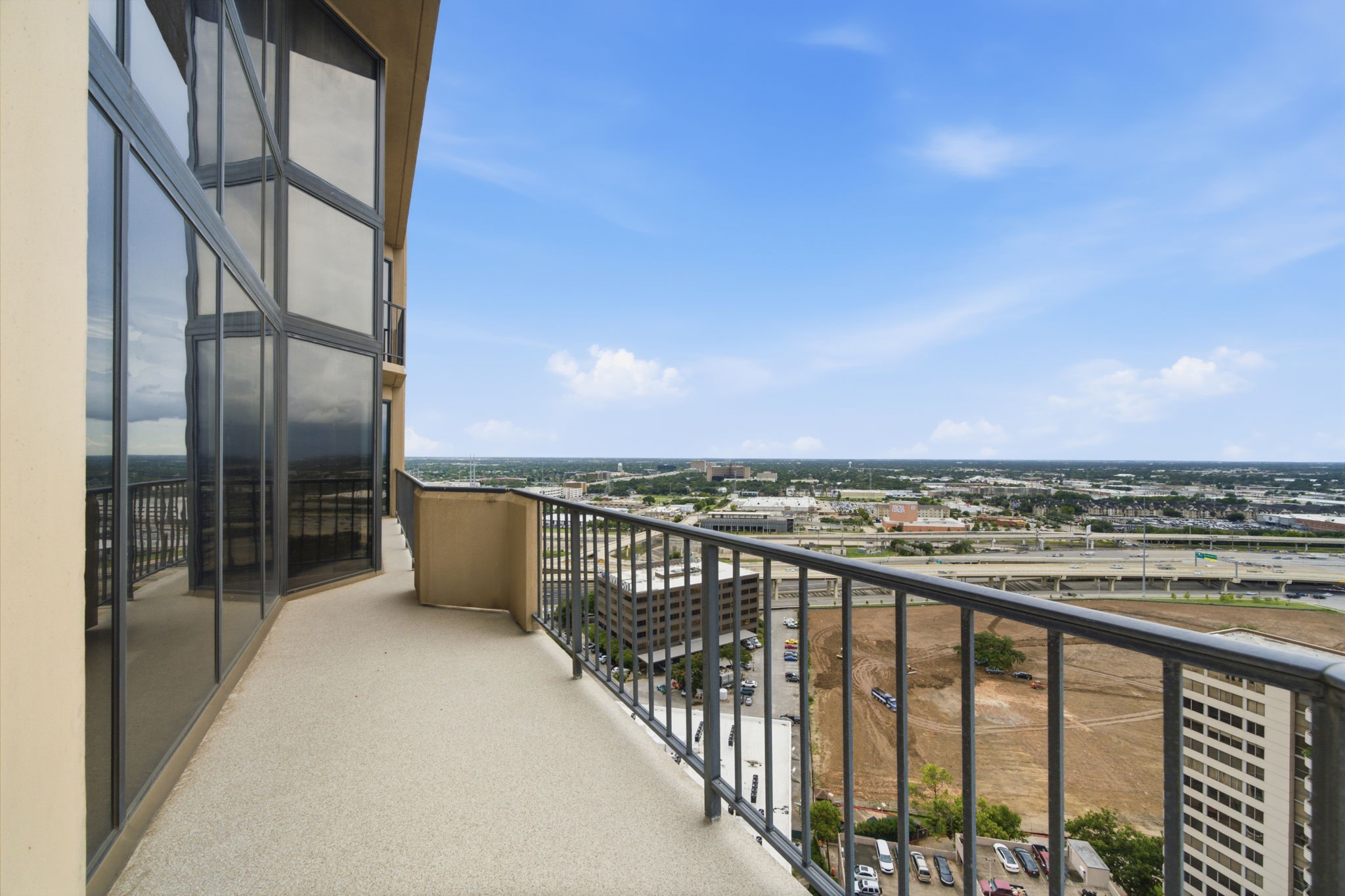 3350 McCue Road, Unit 2402 Houston, TX 77056 - Photo 41 of 49 Soaring high above the city, this sprawling private terrace boasts durable non-slip decking and sleek safety railings that frame vast open-air vistas of the surrounding metropolis. Angled glass exterior walls mirror the skyline, offering an exclusive high-rise vantage point designed for sophisticated outdoor lounging.