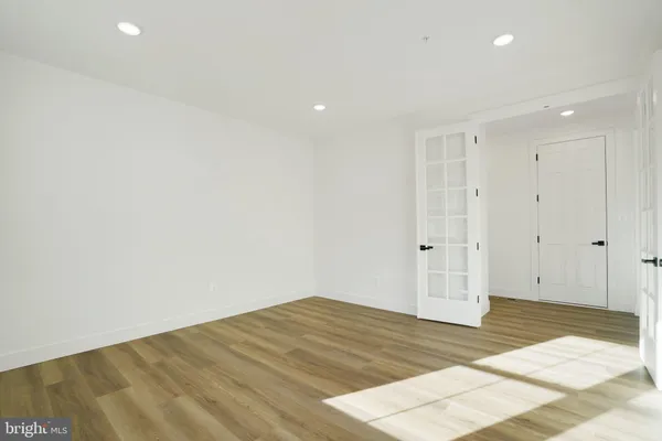 a view of an empty room with wooden floor kitchen and a window