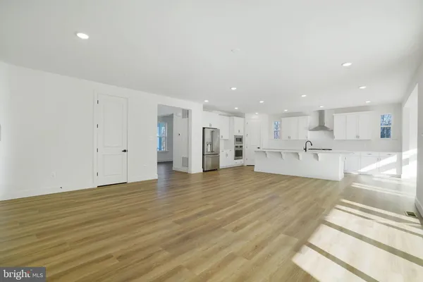 a view of a kitchen with kitchen island a counter top space a sink appliances and a living room
