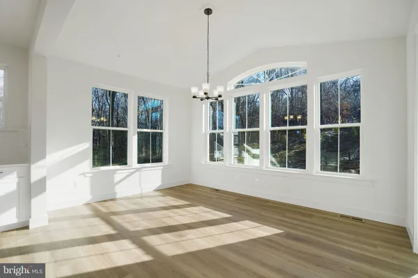 a large white kitchen with kitchen island a sink wooden floor and white cabinets