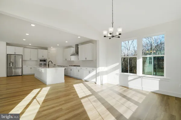 a large white kitchen with kitchen island a sink stainless steel appliances and cabinets