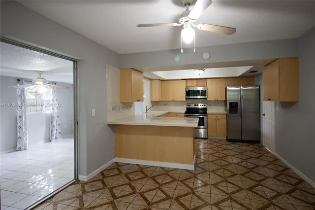 a kitchen with stainless steel appliances kitchen island granite countertop a refrigerator and a sink