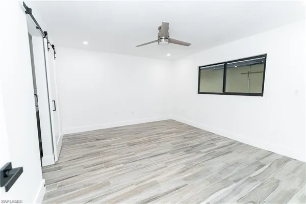 a view of an empty room with wooden floor and a ceiling fan