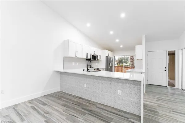 a large kitchen with stainless steel appliances a large counter top a stove and a refrigerator