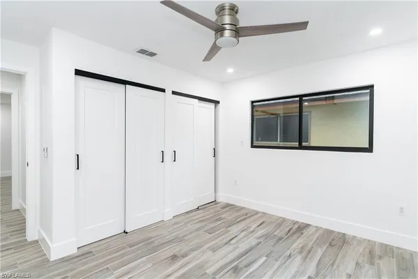 a view of empty room with wooden floor and fan