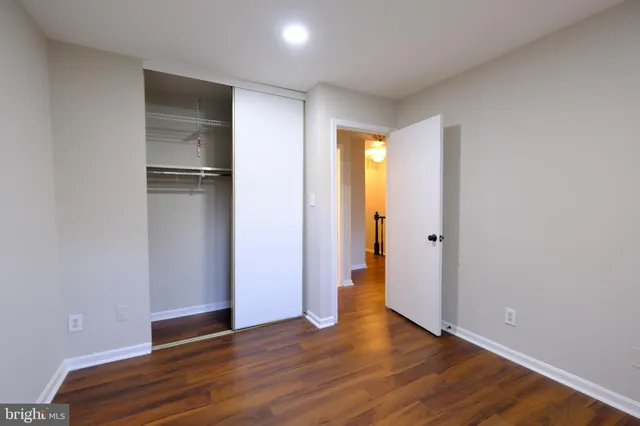 a view of an empty room with wooden floor and closet