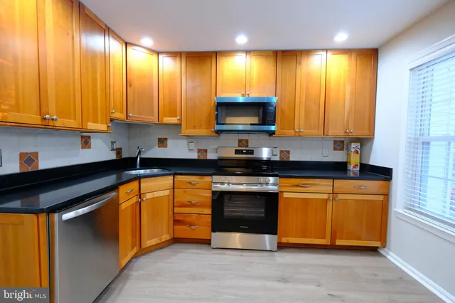 a kitchen with stainless steel appliances granite countertop wooden cabinets a stove top oven a sink and dishwasher