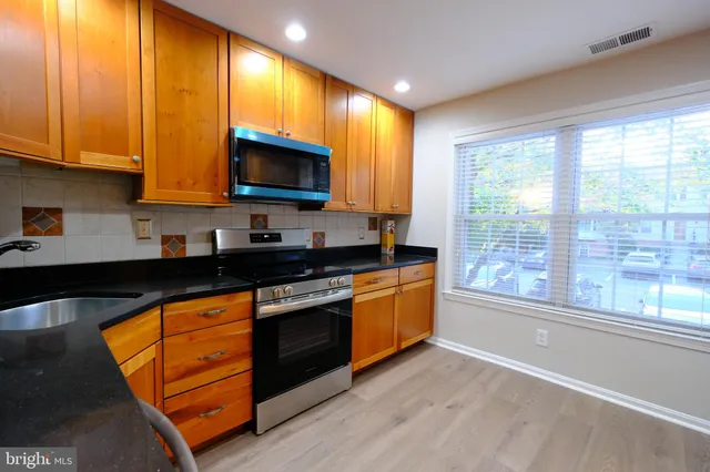 a kitchen with stainless steel appliances granite countertop a stove a sink and a microwave