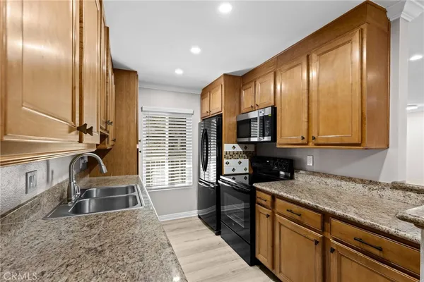 a kitchen with stainless steel appliances granite countertop a sink a stove and a microwave