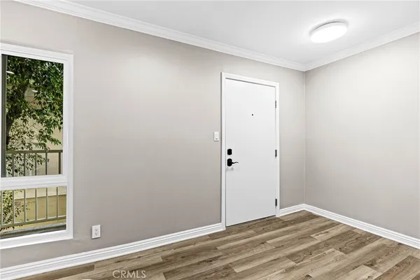 a view of an empty room with wooden floor and a window