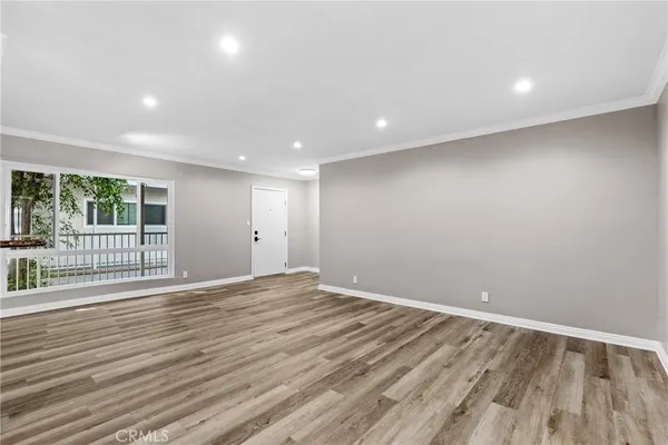 a view of kitchen and empty room with wooden floor