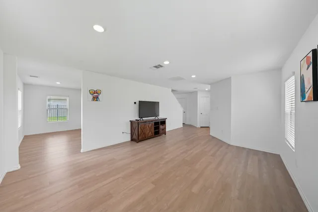 a view of empty room with wooden floor and window