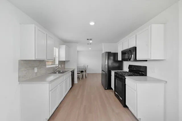 a kitchen with stainless steel appliances a sink stove refrigerator and cabinets