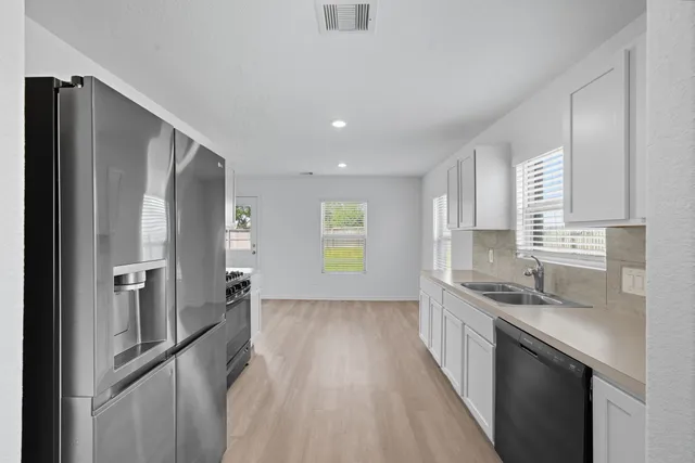 a kitchen with stainless steel appliances granite countertop a sink a stove and a refrigerator