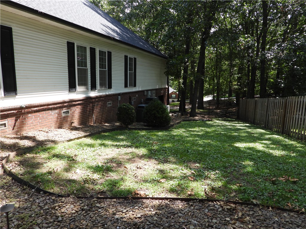 19489 Oak Circle Springdale, AR 72764 - Photo 37 of 58 Expansive side yard featuring a partial privacy fence, lush trees, and a manicured lawn