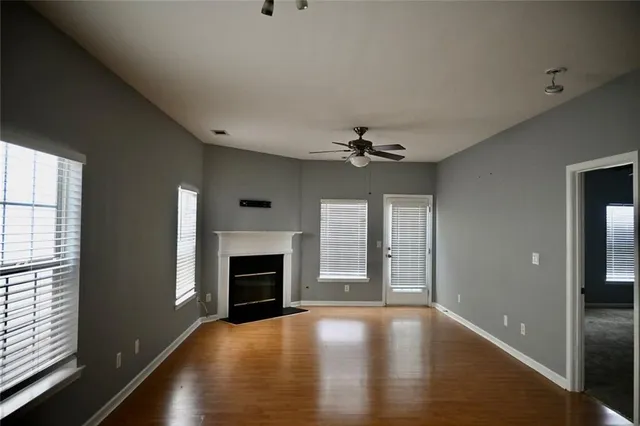 an empty room with windows fireplace and wooden floor