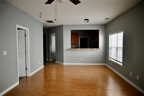 a view of an empty room with a window and wooden floor